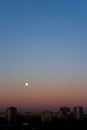 Full moon on clear sunrise sky and buildings under it