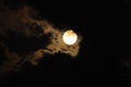 Full moon close-up and eerie white clouds against a black night sky. The big moon on a dark night The clouds gather together in