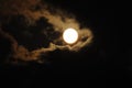 Full moon close-up and eerie white clouds against a black night sky. The big moon on a dark night The clouds gather together in