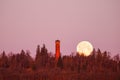Full moon going down by a tower at dawn Royalty Free Stock Photo