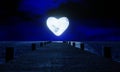 Full moon, heart shape at night was full of stars and a faint mist. A wooden bridge extended into the sea. Fantasy image at night