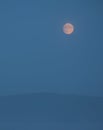 Full moon in the mountains in the early morning with a mountain cliff and dense clouds in the valley Royalty Free Stock Photo