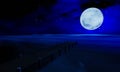 The full moon at night was full of stars and a faint mist. A wooden bridge extended into the sea. Fantasy image at night, super Royalty Free Stock Photo