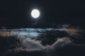 Full moon over clouds and fog in night sky, nebulous blurry landscape