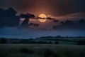 Full moon peeks through dark clouds, casting an eerie glow