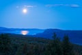 Full moon reflects in water surface of lake deep in Swedish arctic. Night in remote Lapland wilderness. Tjaktjajavrre Royalty Free Stock Photo