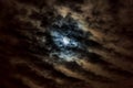 Full moon rises behind strong clouds in a clear night