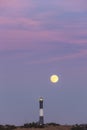 Full moon rising behind a tall stone lighthouse just after sunset. Fire Island Royalty Free Stock Photo