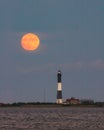 Full moon rising through a hazy horizon behind a beautiful lighthouse. Fire Island, NY Royalty Free Stock Photo