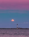 Full moon rising through a hazy horizon behind a beautiful lighthouse. Fire Island, NY Royalty Free Stock Photo