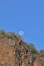 full moon setting behind the cliffs as sun rises in hell\'s gate national park, naivasha, kenya Royalty Free Stock Photo