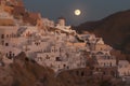 A full moon shines over a city on a hillside. AI generative image