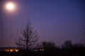 The full moon shining brightly in the night sky above the artificial light Royalty Free Stock Photo