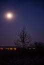 The full moon shining brightly in the night sky above the artificial light Royalty Free Stock Photo