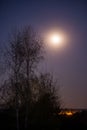 The full moon shining brightly in the night sky above the artificial light Royalty Free Stock Photo