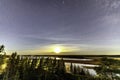 Full moon and stars in clear sky shines over Scandinavian wild forest, lakes, swamps, long exposure night photo, autumn, virgin