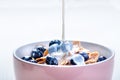 Full muesli bowl on a white table with blueberry and milk splash. Healthy breakfast cereals with milk, seed, fruit. Oat flakes Royalty Free Stock Photo