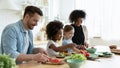 Full multinational family preparing dietary vegetable salad in kitchen Royalty Free Stock Photo