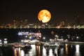 full oak blood moon and night lights of pier and beach and reflection color on water surface of light of city Royalty Free Stock Photo