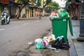 Full over capacity green dust bin on old town street in Hanoi, Vietnam