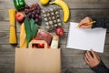 Full paper bag different food on wooden table