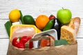 Full paper bag of different healthy food on white wooden background. fruits, vegetables, fish and chicken meat Royalty Free Stock Photo