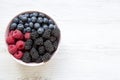 Full pink bowl of fresh berries: blackberry, raspberry, blueberry, view from above. Summer berry. Top view, overhead.