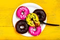 A full plate of donuts. Lots of colored donuts on a paper plate. View from above.