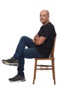 Full portrait of a bald man sitting sideways on white background, Royalty Free Stock Photo