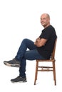 Full portrait of a bald man sitting sideways on white background Royalty Free Stock Photo
