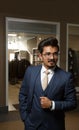 Full portrait of a handsome businessman wearing elegant suit and glasses against the backdrop of a shop with clothes. Men`s beaut Royalty Free Stock Photo