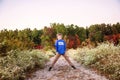 Full portrait of a smiling nine year old boy outside on a path lined by flowers with colorful fall trees Royalty Free Stock Photo