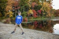 Full portrait of a smiling nine year old boy outside by a lake with colorful fall trees