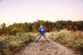 Full portrait of a smiling nine year old boy outside on a path lined by flowers with colorful fall trees