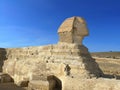 Full profile of Great Sphinx including pyramids in the background on a clear sunny, blue sky day in Giza, Cairo, Egypt with no Royalty Free Stock Photo