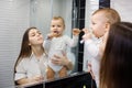 Full of proud mother looking at her baby son brushing his teeth in bathroom. Royalty Free Stock Photo