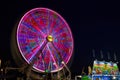 Full purple ferris wheel at night with vendors for carnival county fair