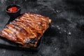 Full rack of BBQ grilled pork spare ribs on a marble board. Black background. Top view. Copy space Royalty Free Stock Photo