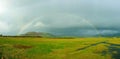 A full rainbow over rural green farmland landscape showing wet rainy weather