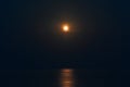 The Full Red Moon Shines Brightly in the Sky on a Dark Night Over the Calm Sea. Beautiful Moon Path on the Water Royalty Free Stock Photo