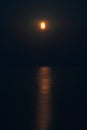 The Full Red Moon Shines Brightly in the Sky on a Dark Night Over the Calm Sea. Beautiful Moon Path on the Water Royalty Free Stock Photo