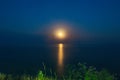 The Full Red Moon Shines Brightly in the Sky on a Dark Night Over the Calm Sea. Beautiful Moon Path on the Water Royalty Free Stock Photo