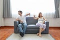 Full shot of asian pregnant wife and caucasian husband sitting on sofa in living room with angry motion and showing thumb down or Royalty Free Stock Photo