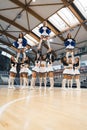 Full shot of a cheerleading squad doing three extension stunts at the same time. Sport concept. Vertical photo.