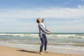 Full shot of a smily teenager jumping in the seashore of the beach in a clear day. Easter. Royalty Free Stock Photo