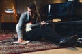 full shot of a young guitarist man sitting on the floor with a bass guitar and writing notes in the studio Royalty Free Stock Photo