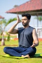 full shot of Young man doing nostril breathing exercise or pranayama yoga by eyes closed at park - concept of zen Royalty Free Stock Photo