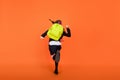 Full size back view photo of young girl hold rucksack go run hurry school lesson isolated over orange color background