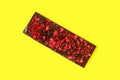 Full size bar of black chocolate with pieces of red raspberries isolated on yellow Royalty Free Stock Photo