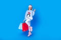 Full size body of friendly positive jump woman ready for shopping happy new year party show v sign isolated on blue